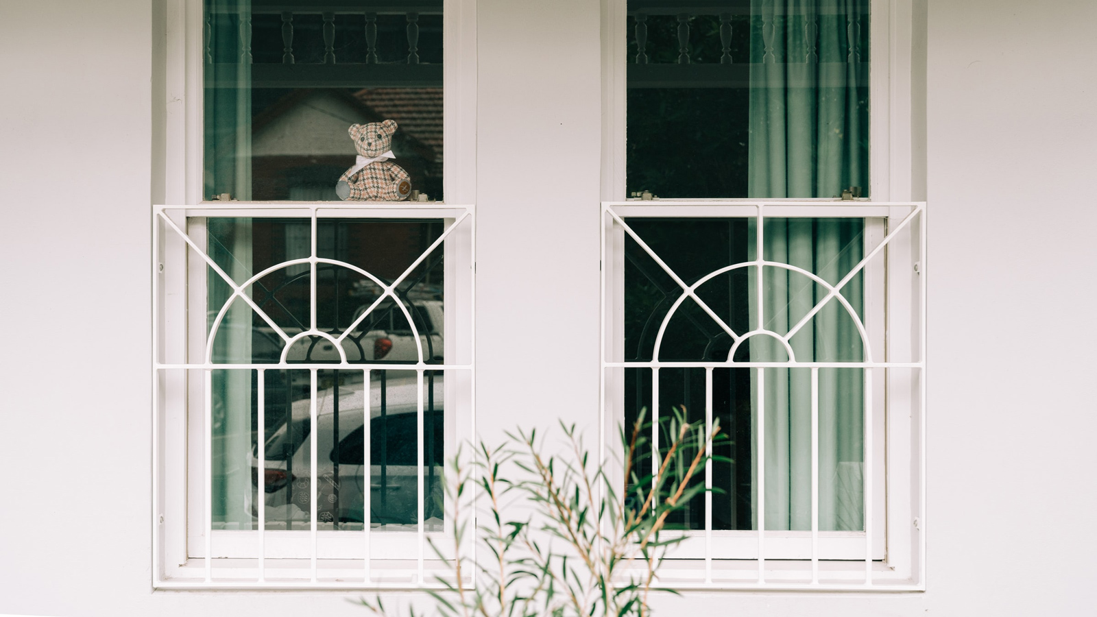 Photo of a teddy bear in a window on a white-painted house
